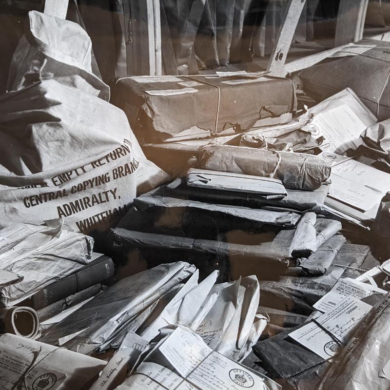Black and white photograph of piles of parcels and bags containing letters all crowded together